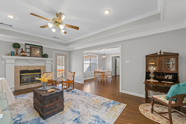 living room with dark hardwood / wood-style flooring, crown molding, a fireplace, and ceiling fan