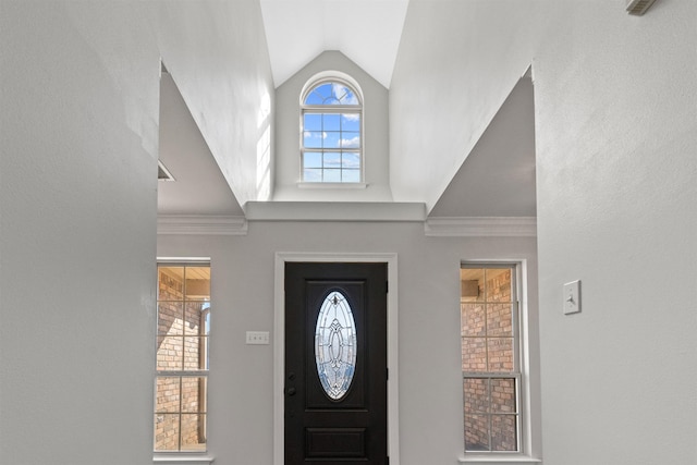 entryway with high vaulted ceiling, plenty of natural light, and ornamental molding