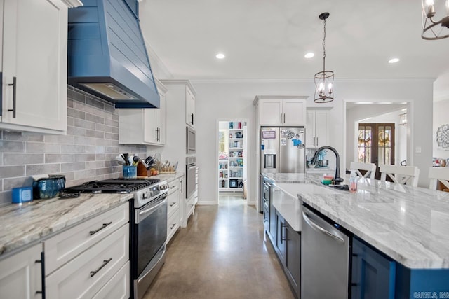 kitchen featuring premium range hood, decorative light fixtures, white cabinetry, sink, and stainless steel appliances