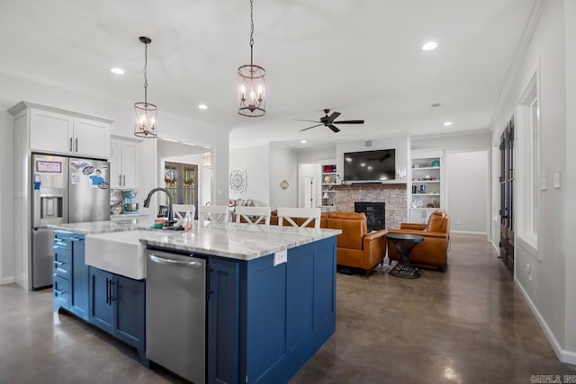 kitchen with appliances with stainless steel finishes, blue cabinets, white cabinetry, an island with sink, and hanging light fixtures