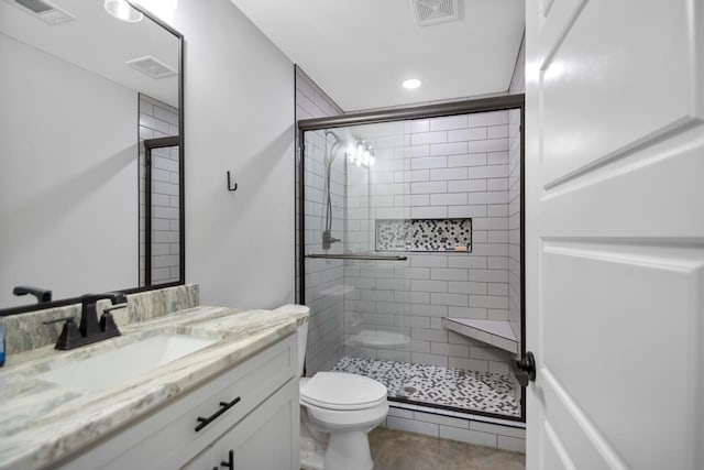 bathroom with vanity, a shower with shower door, and toilet