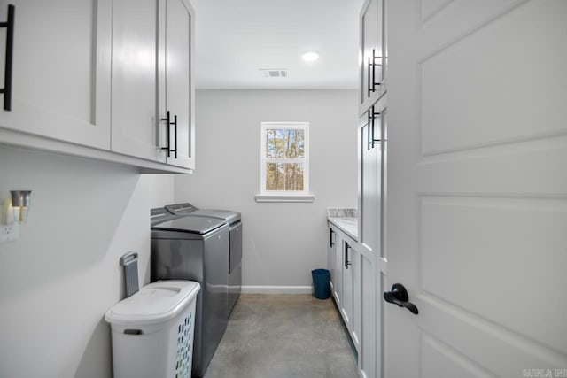 clothes washing area featuring cabinets and washer and clothes dryer