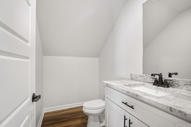 bathroom featuring vanity, vaulted ceiling, hardwood / wood-style floors, and toilet