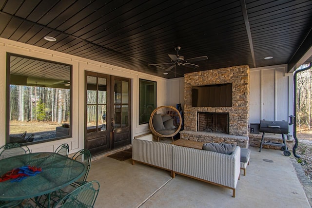 view of patio / terrace featuring ceiling fan, french doors, and an outdoor stone fireplace