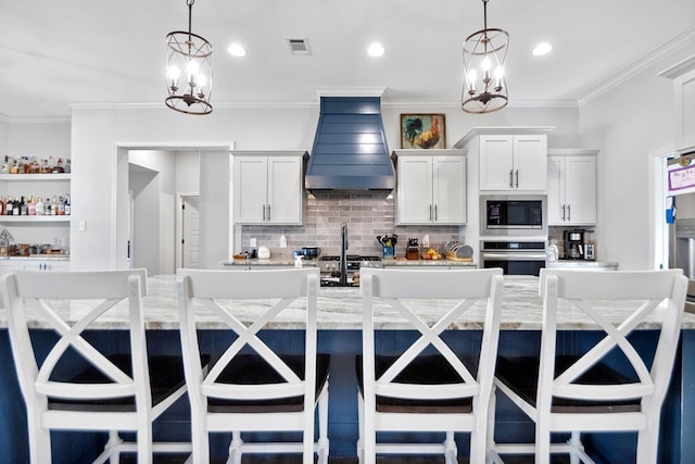 kitchen with pendant lighting, appliances with stainless steel finishes, a large island, and custom exhaust hood