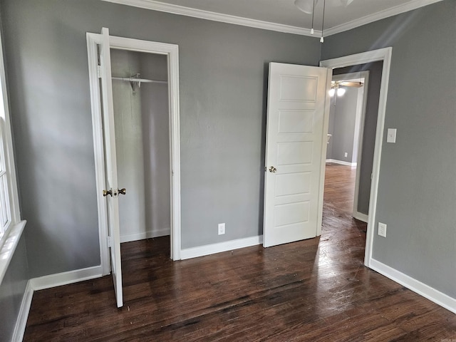 unfurnished bedroom with dark wood-type flooring, crown molding, and a closet