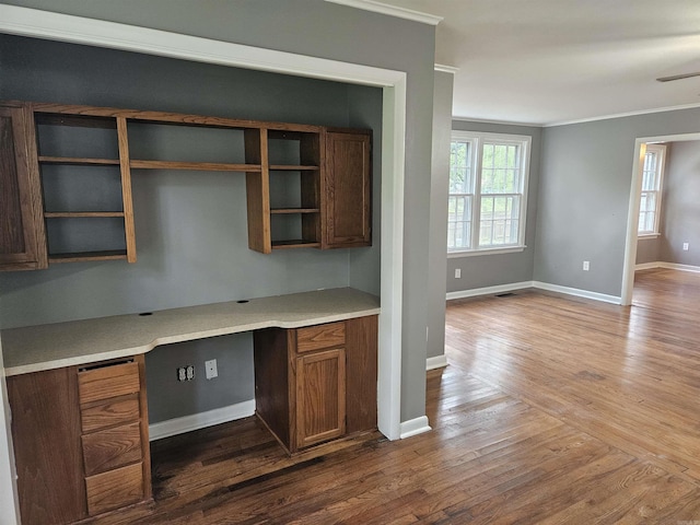 interior space with crown molding, hardwood / wood-style flooring, and built in desk