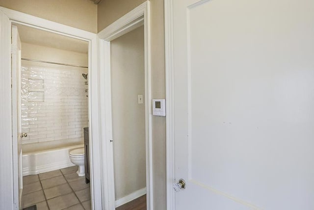 bathroom featuring toilet, tiled shower / bath combo, and tile patterned flooring