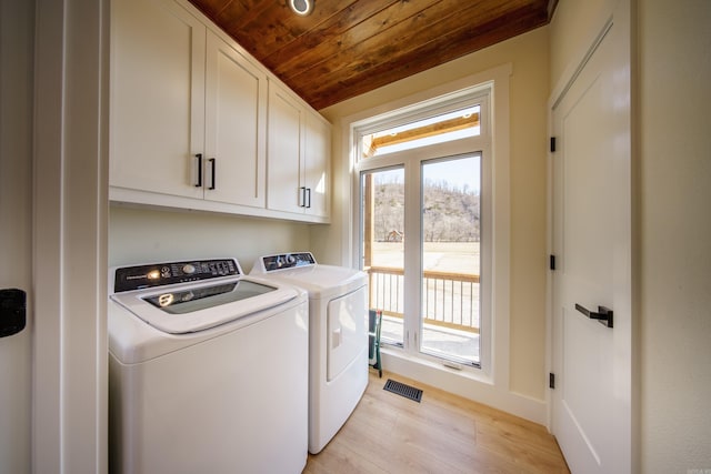 clothes washing area featuring cabinets, separate washer and dryer, light wood-type flooring, and wooden ceiling