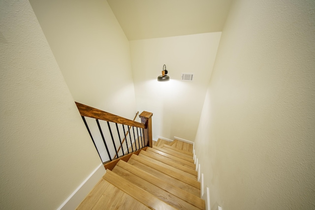 staircase with hardwood / wood-style flooring and vaulted ceiling