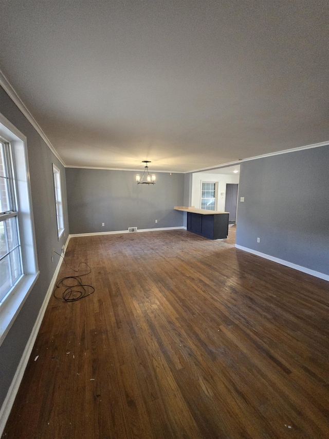 unfurnished living room featuring an inviting chandelier, ornamental molding, and dark hardwood / wood-style flooring