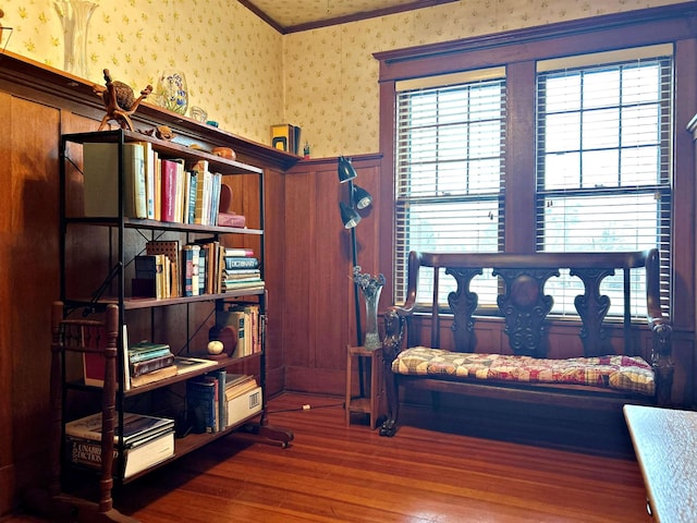 living area with ornamental molding, wood-type flooring, and plenty of natural light