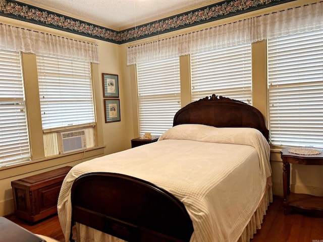 bedroom with hardwood / wood-style floors, cooling unit, and a textured ceiling