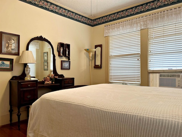 bedroom with cooling unit, wood-type flooring, and a textured ceiling