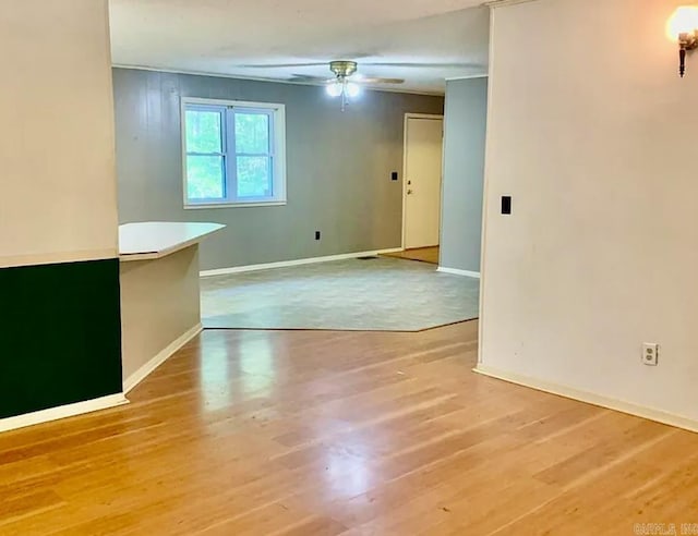 spare room with baseboards, light wood-style floors, and ceiling fan