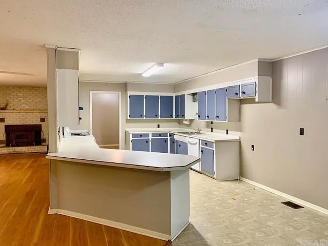 kitchen with blue cabinets, visible vents, a textured ceiling, a peninsula, and a brick fireplace