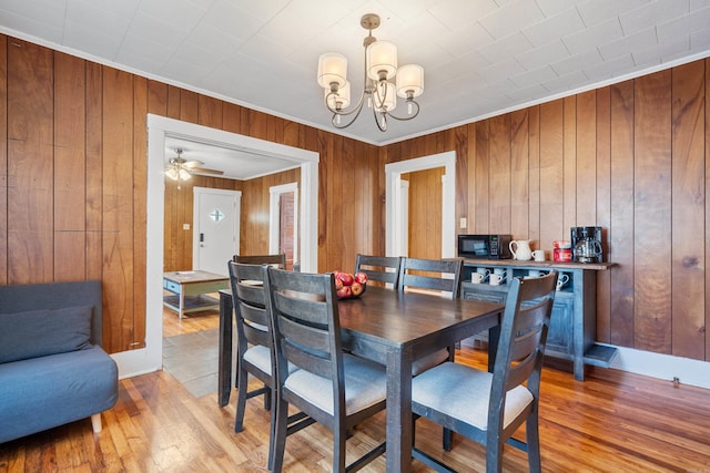 dining space with a notable chandelier, light wood-type flooring, and wood walls