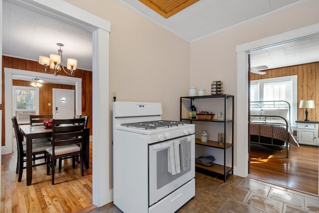 kitchen with crown molding, gas range gas stove, and wood walls