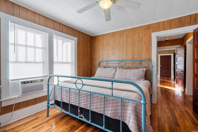 bedroom featuring cooling unit, hardwood / wood-style floors, and wooden walls