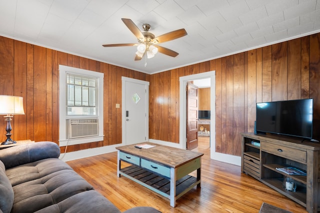 living room with ceiling fan, cooling unit, light hardwood / wood-style floors, and wood walls