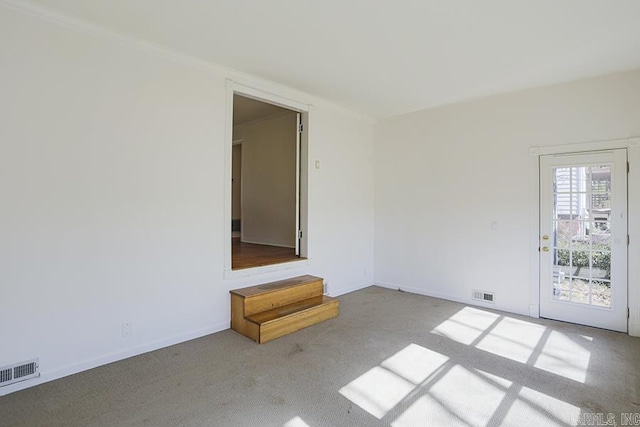 carpeted spare room featuring crown molding