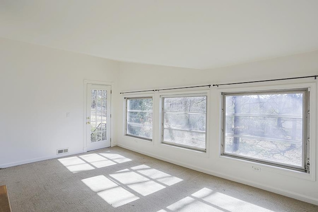 unfurnished room featuring a wealth of natural light and light colored carpet