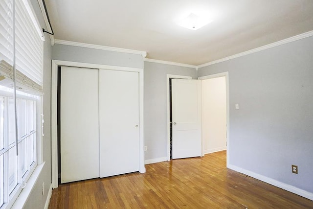 unfurnished bedroom featuring hardwood / wood-style flooring, ornamental molding, and a closet