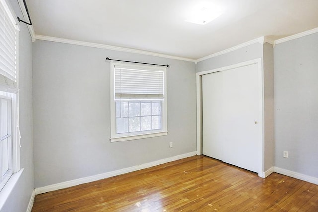 unfurnished bedroom with ornamental molding, light wood-type flooring, and a closet