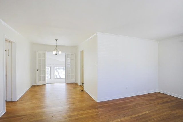 empty room with crown molding, hardwood / wood-style flooring, french doors, and an inviting chandelier