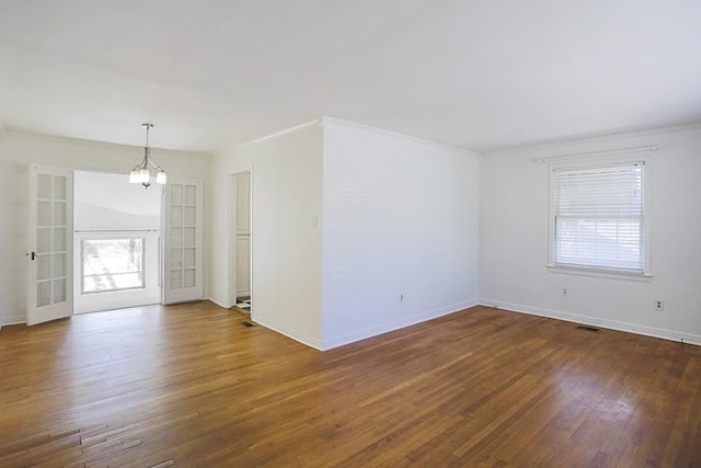 spare room featuring crown molding, dark wood-type flooring, and a chandelier