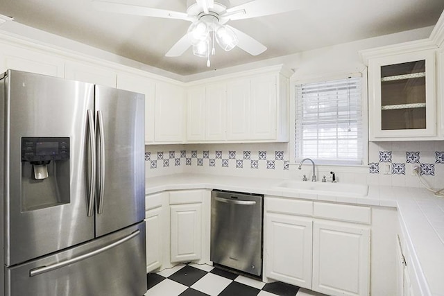 kitchen featuring sink, white cabinetry, tile countertops, appliances with stainless steel finishes, and ceiling fan