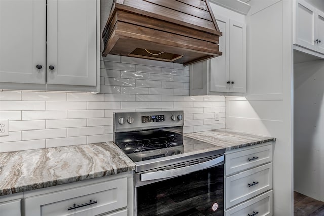 kitchen featuring tasteful backsplash, light stone countertops, white cabinets, stainless steel electric stove, and custom exhaust hood