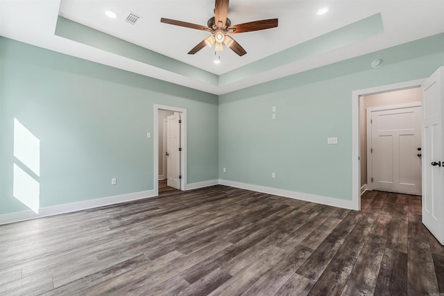 spare room with a raised ceiling, dark wood-type flooring, and ceiling fan