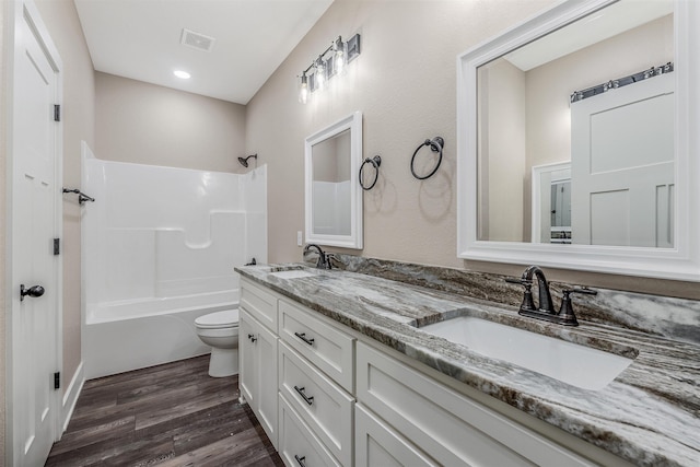 full bathroom featuring hardwood / wood-style flooring, vanity, tub / shower combination, and toilet