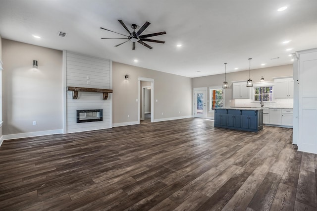 unfurnished living room featuring sink, a large fireplace, dark hardwood / wood-style floors, and ceiling fan