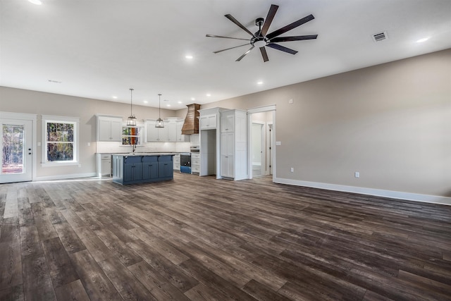 unfurnished living room featuring sink, hardwood / wood-style flooring, and ceiling fan