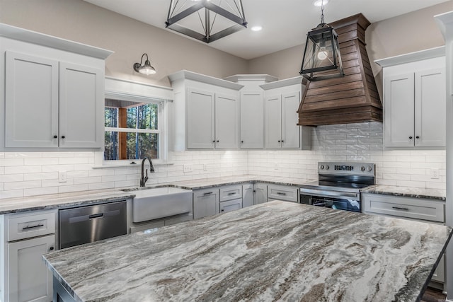 kitchen with appliances with stainless steel finishes, decorative light fixtures, sink, backsplash, and light stone counters