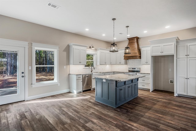 kitchen featuring white cabinetry, hanging light fixtures, appliances with stainless steel finishes, and premium range hood