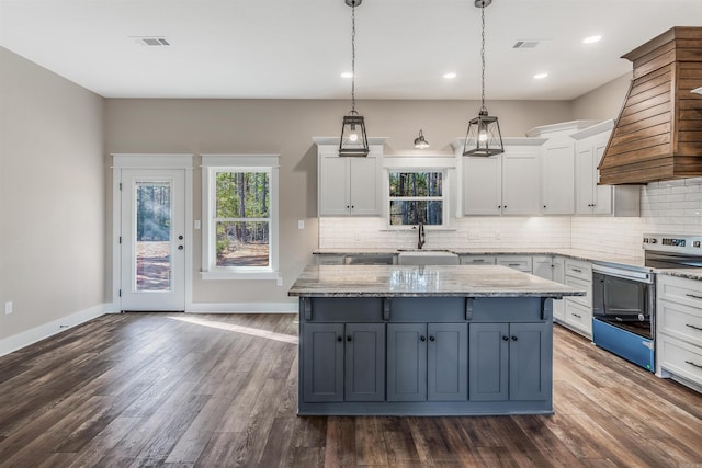 kitchen with sink, white cabinets, stainless steel range with electric cooktop, hanging light fixtures, and a center island