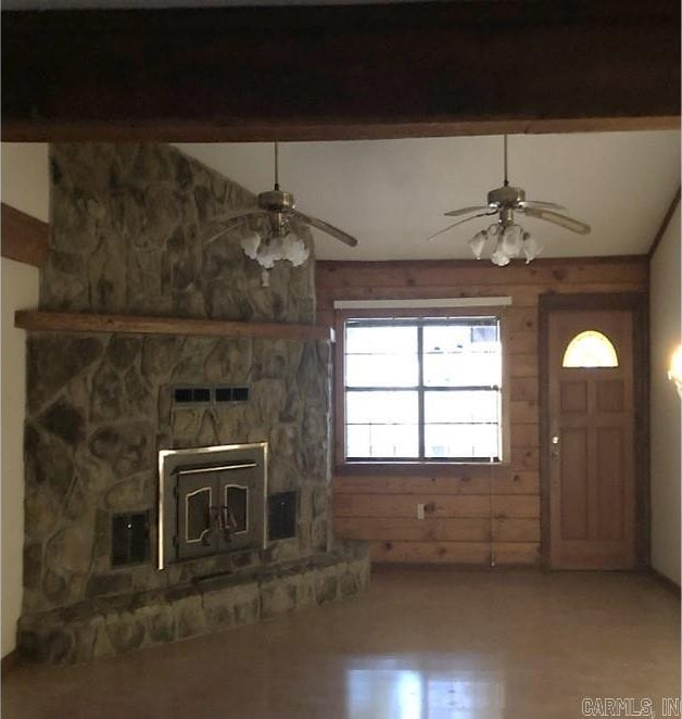 unfurnished living room featuring ceiling fan, beam ceiling, and wood walls