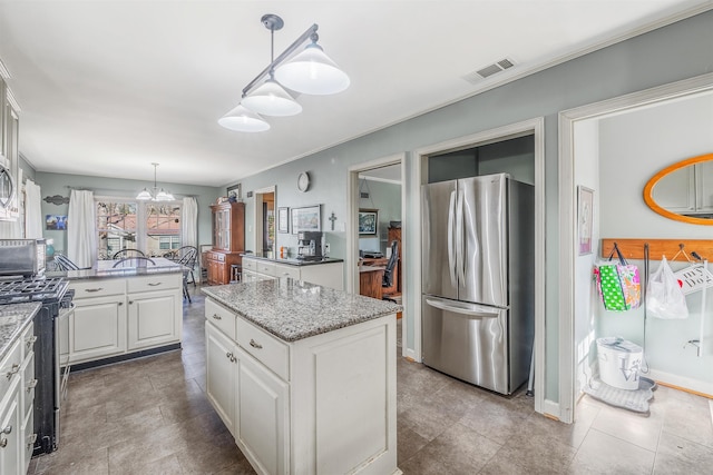 kitchen featuring pendant lighting, appliances with stainless steel finishes, white cabinetry, light stone counters, and a kitchen island