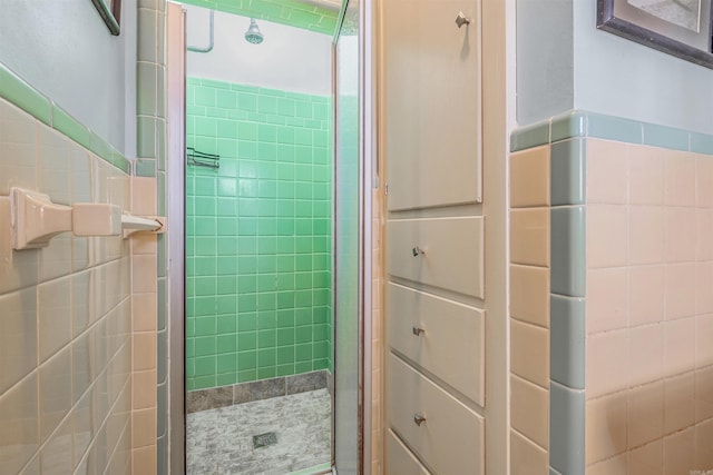 bathroom featuring a shower with shower door and tile walls