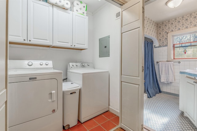 laundry area with tile walls, cabinets, light tile patterned floors, washing machine and clothes dryer, and electric panel