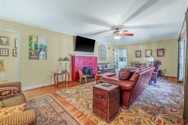 living room featuring crown molding, hardwood / wood-style floors, ceiling fan, and a fireplace