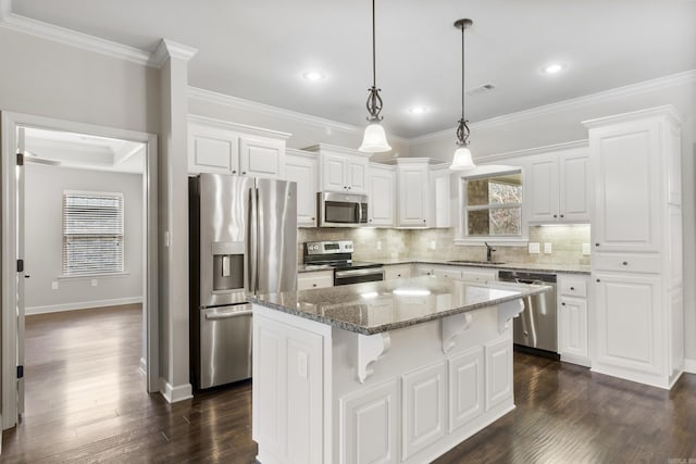 kitchen featuring white cabinetry, stainless steel appliances, a kitchen island, decorative light fixtures, and dark stone counters