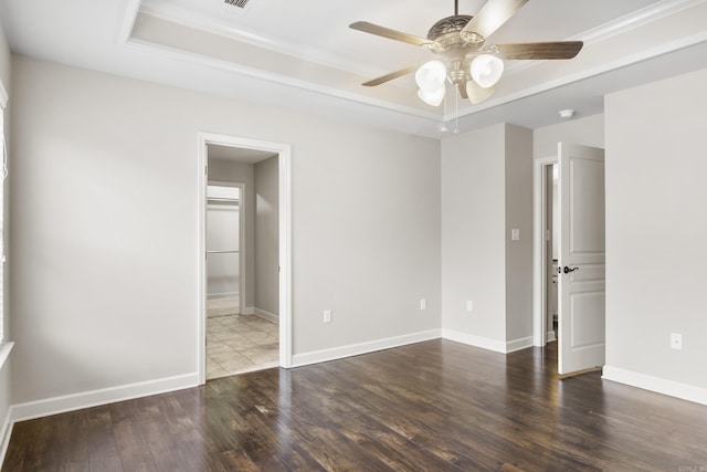 unfurnished room with a raised ceiling, ceiling fan, and dark hardwood / wood-style flooring