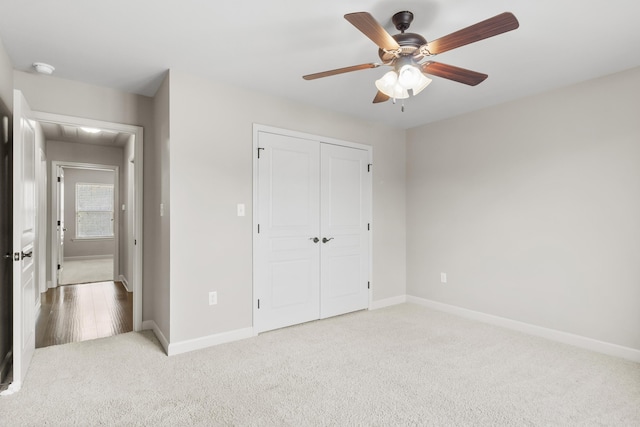 unfurnished bedroom with ceiling fan, light colored carpet, and a closet