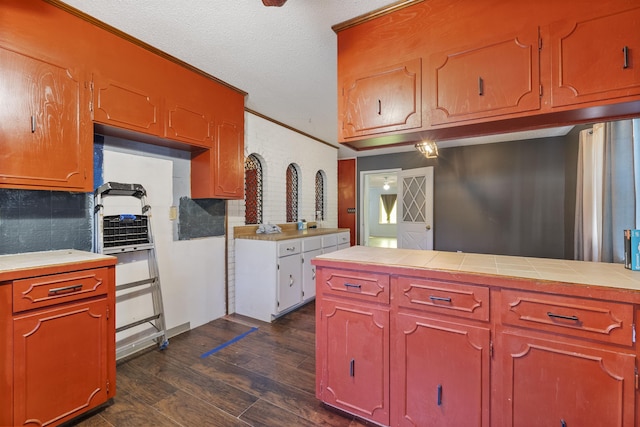 kitchen with crown molding, dark wood-type flooring, tile countertops, and a textured ceiling