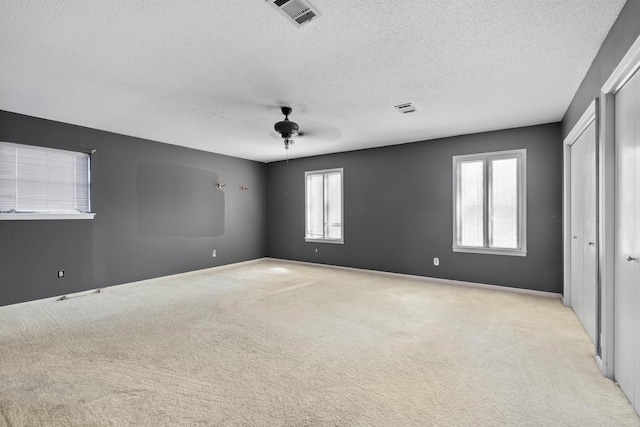 unfurnished room with ceiling fan, light colored carpet, and a textured ceiling