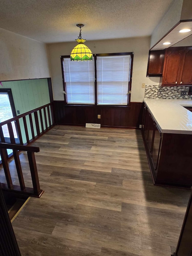 unfurnished dining area featuring hardwood / wood-style flooring, a healthy amount of sunlight, and a textured ceiling